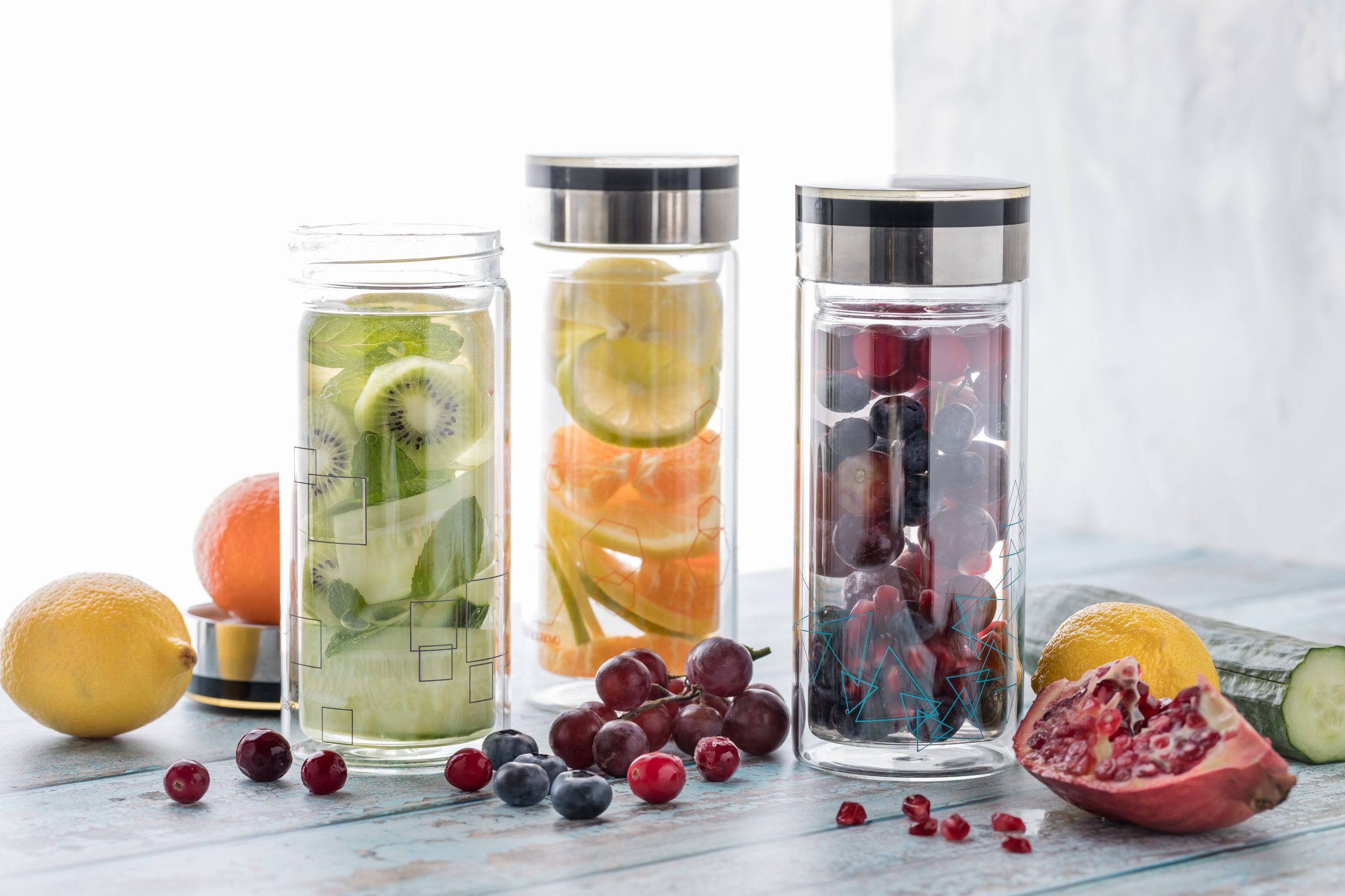 A close up of three bottles of different fruit and vegetable infused flavoured water against a bright background.